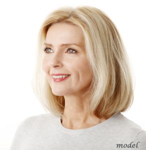 Close-up portrait of beautiful mature woman standing against white background.